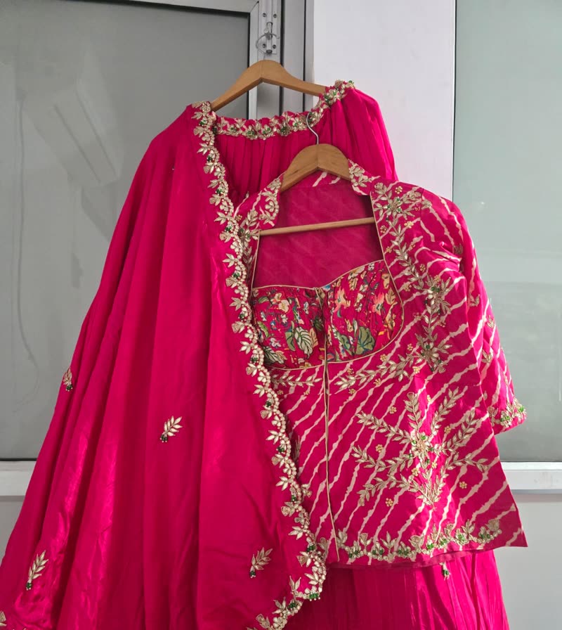 A pink lehenga photographed on a hanger